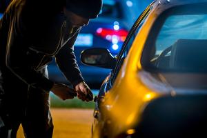 Image showing a person breaking into a car at night.