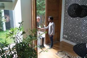 Man welcoming guest into home